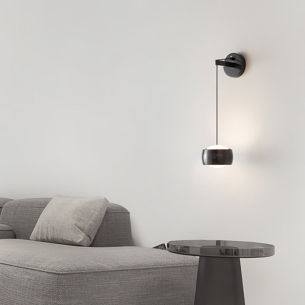 Black Clérachic wall light on a pale wall above a grey sofa and a smoked-glass side table.