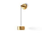 Brass Clérachic wall light on a white backdrop, the rounded shade hanging low below a brass backplate and black cable.