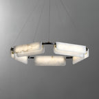 The Clérachic Delia chandelier lit on grey, its alabaster blocks glowing around the dark frame.
