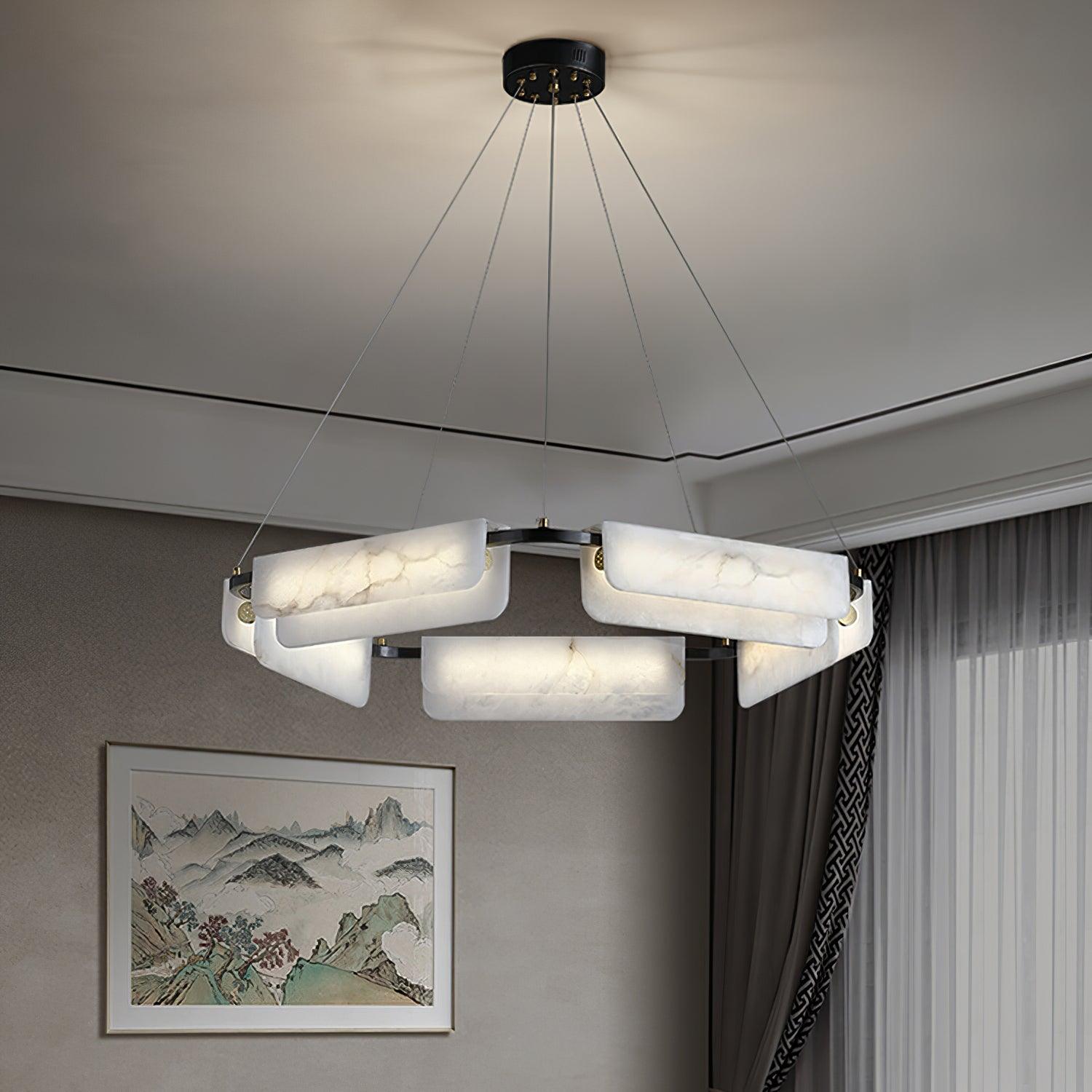 The Clérachic Delia chandelier lit in a room with a framed landscape painting and long curtains.