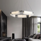 Clérachic Delia chandelier lit in a dark living room with grey drapes and a stone fireplace.