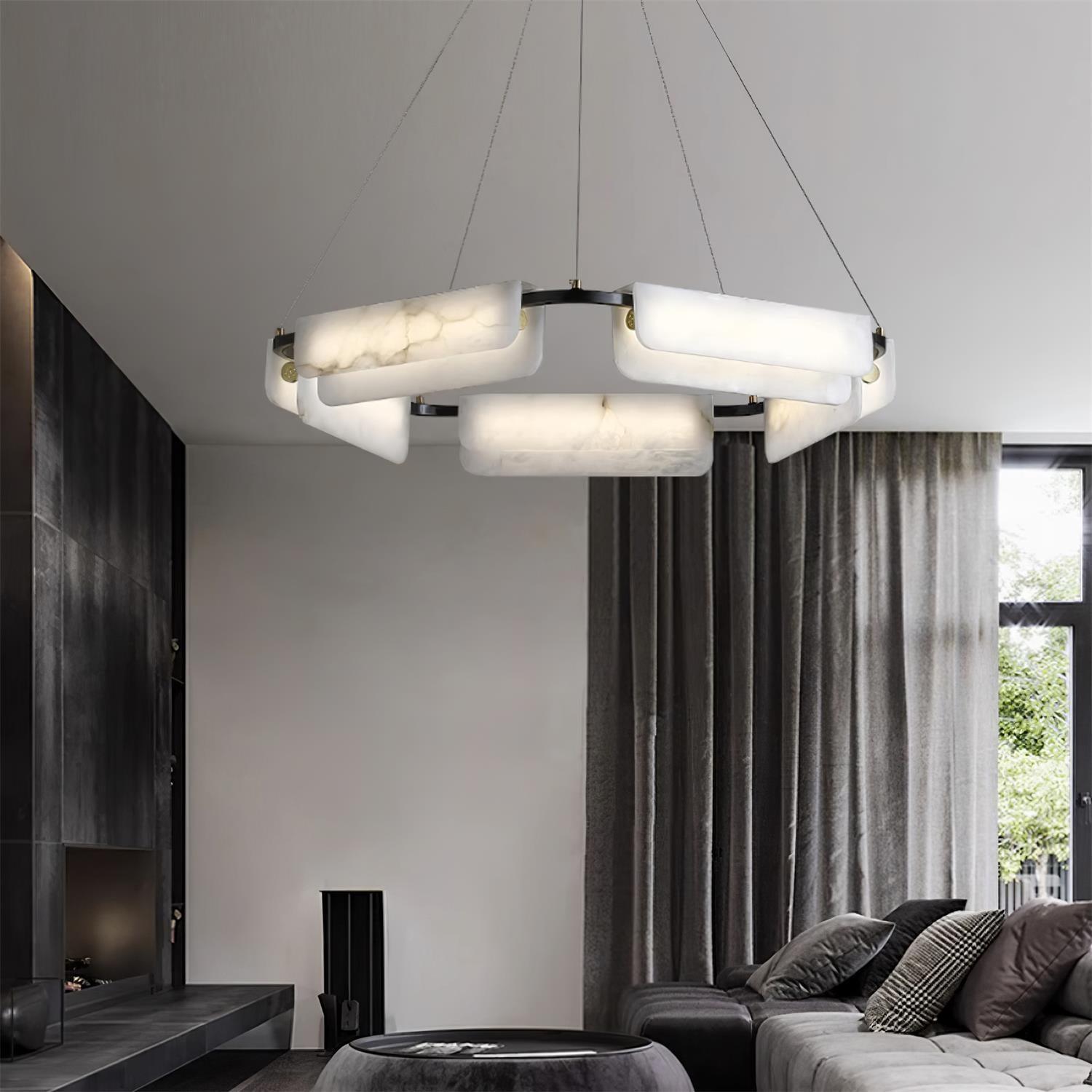 Clérachic Delia chandelier lit in a dark living room with grey drapes and a stone fireplace.
