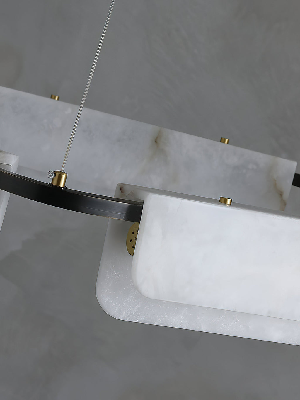 Detail of the Clérachic Delia chandelier's alabaster panels held by brass discs against the black ring, natural veining visible.