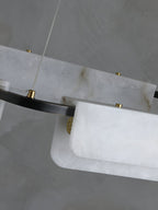 Detail of the Clérachic Delia chandelier's alabaster panels held by brass discs against the black ring, natural veining visible.