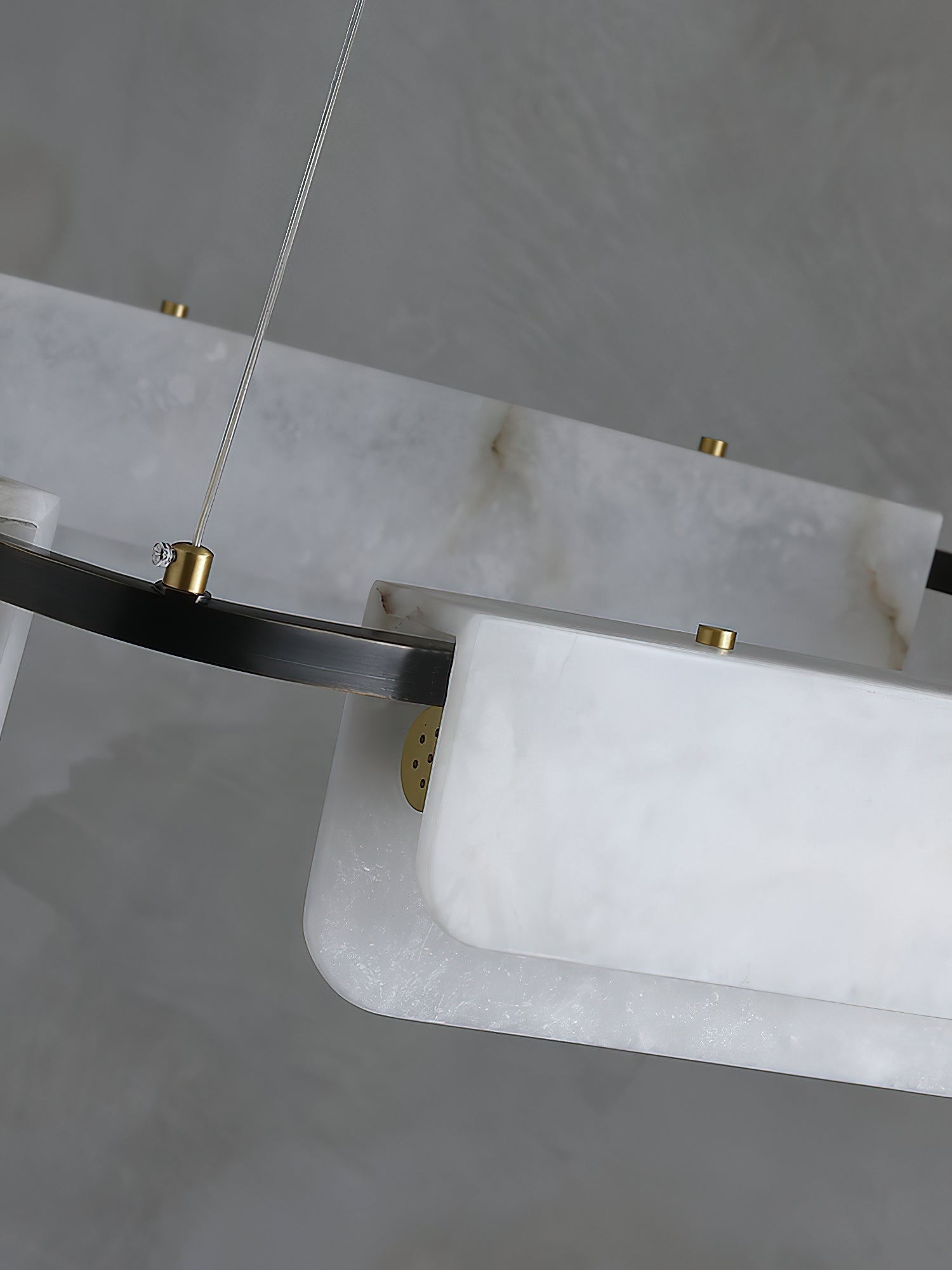 Detail of the Clérachic Delia chandelier's alabaster panels held by brass discs against the black ring, natural veining visible.