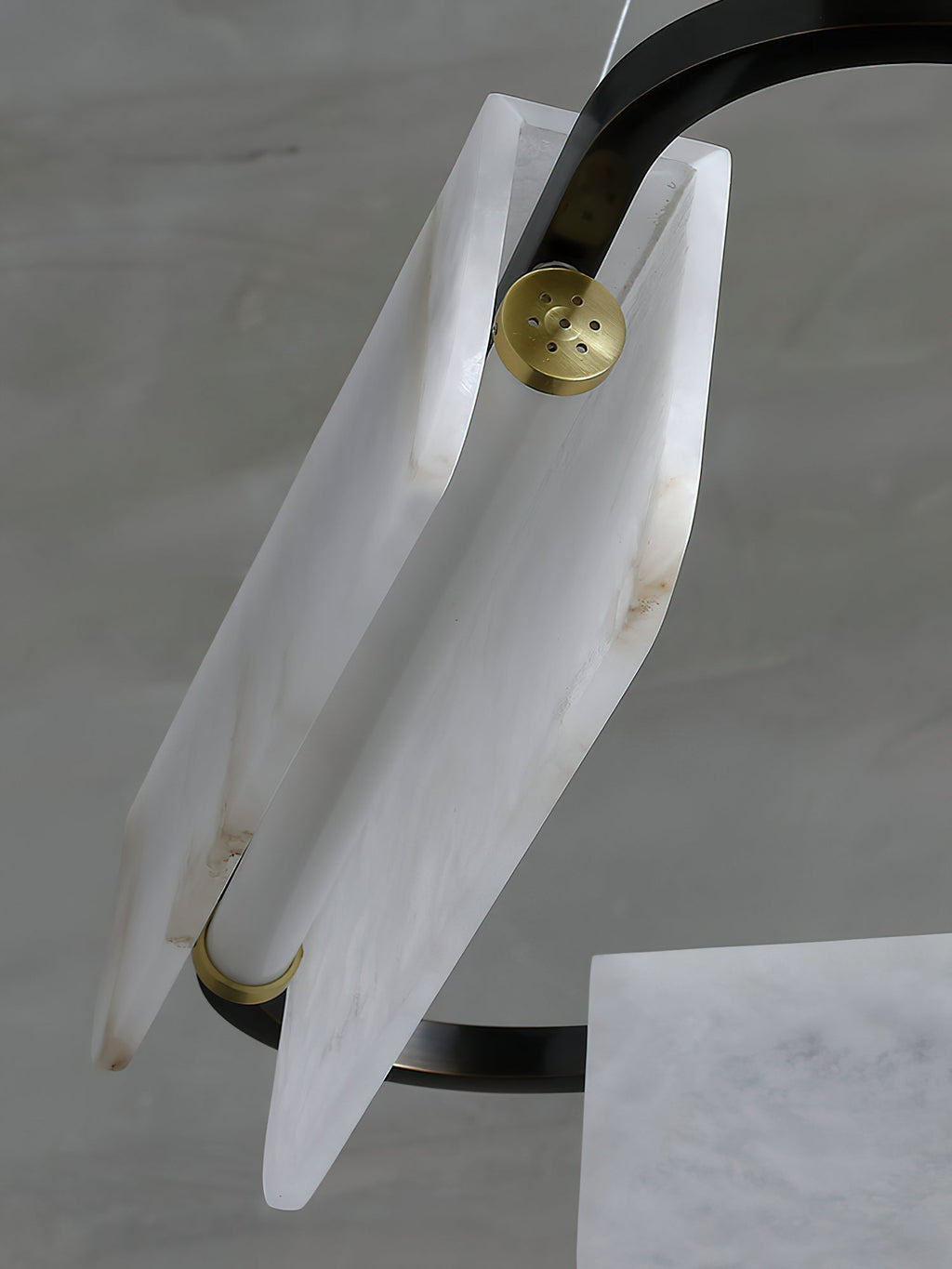 Angled view of an alabaster panel on the Clérachic Delia chandelier, secured by a perforated brass disc.