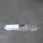 The five-head Clérachic Delia chandelier unlit against concrete, showing the full spread of its alabaster panels.