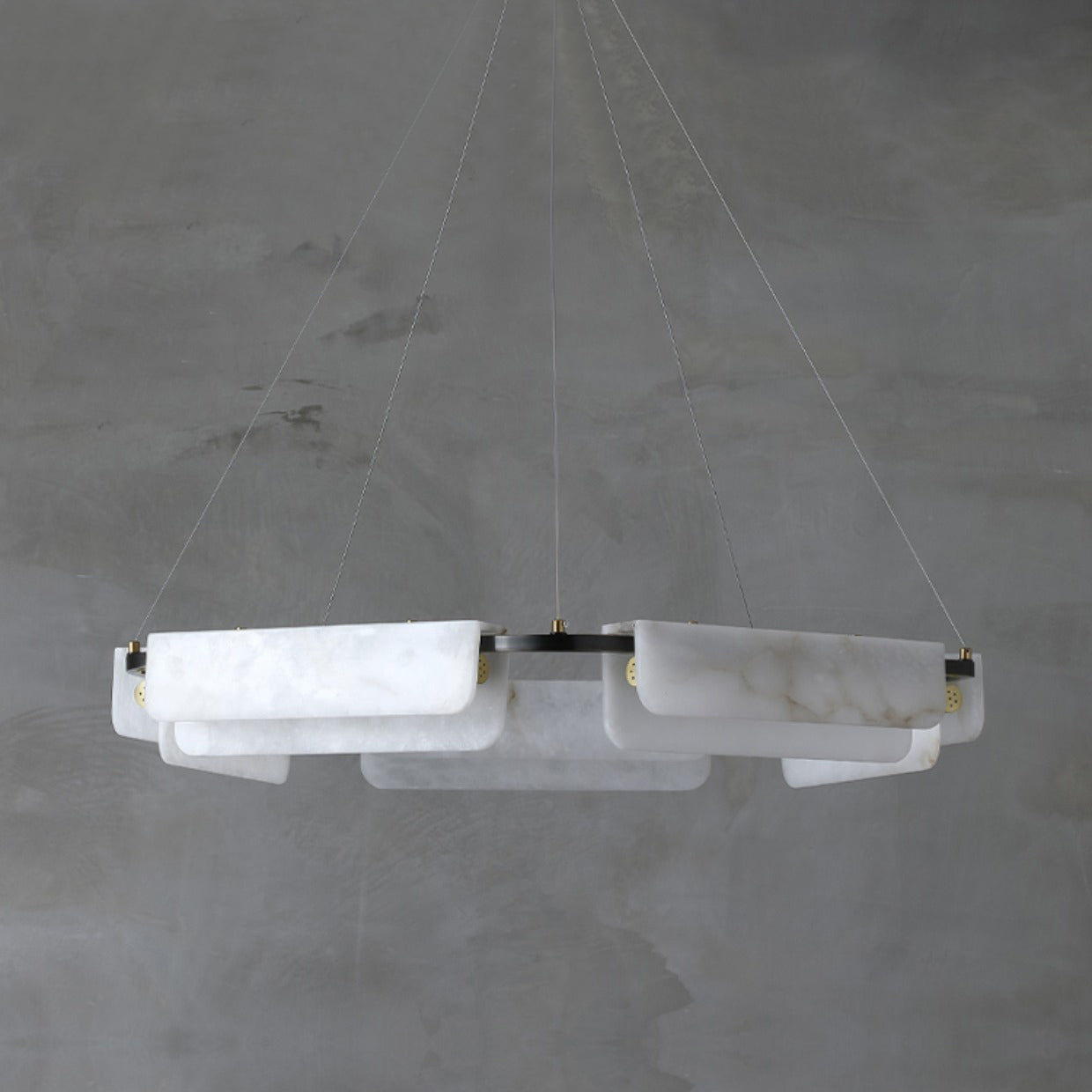 The five-head Clérachic Delia chandelier unlit against concrete, showing the full spread of its alabaster panels.