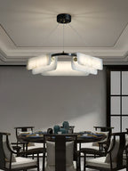 Clérachic Delia chandelier lit above a round dining table set for a meal, in a room with a recessed ceiling.