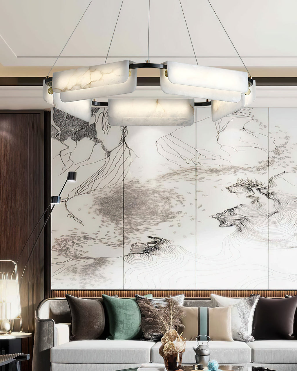 Clérachic Delia chandelier lit in front of a large ink-wash mountain screen above a long pale sofa.