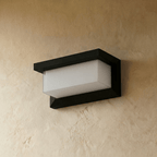 Clérachic black horizontal outdoor wall lamp with a frosted white diffuser, switched off and mounted on a plaster wall