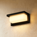 Clérachic black horizontal outdoor wall lamp in a larger size, its frosted diffuser glowing warm white on a plaster wall