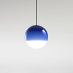 The Clérachic dipped gradient glass pendant light in cobalt blue, hanging alone against a pale studio wall.