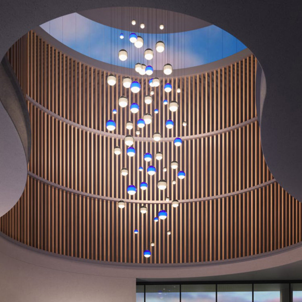 Dozens of Clérachic dipped gradient glass pendant lights massed down a double-height atrium beside a slatted timber wall.