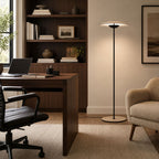 A Clérachic floor lamp glows beside a dark wood desk and bookshelves in a home office, next to a cream boucle armchair.