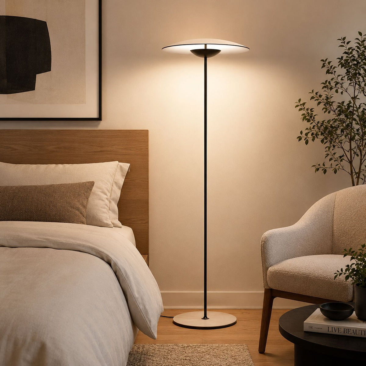 Lit softly beside a bed with a wooden headboard, a Clérachic floor lamp stands near a cream armchair and a potted tree.