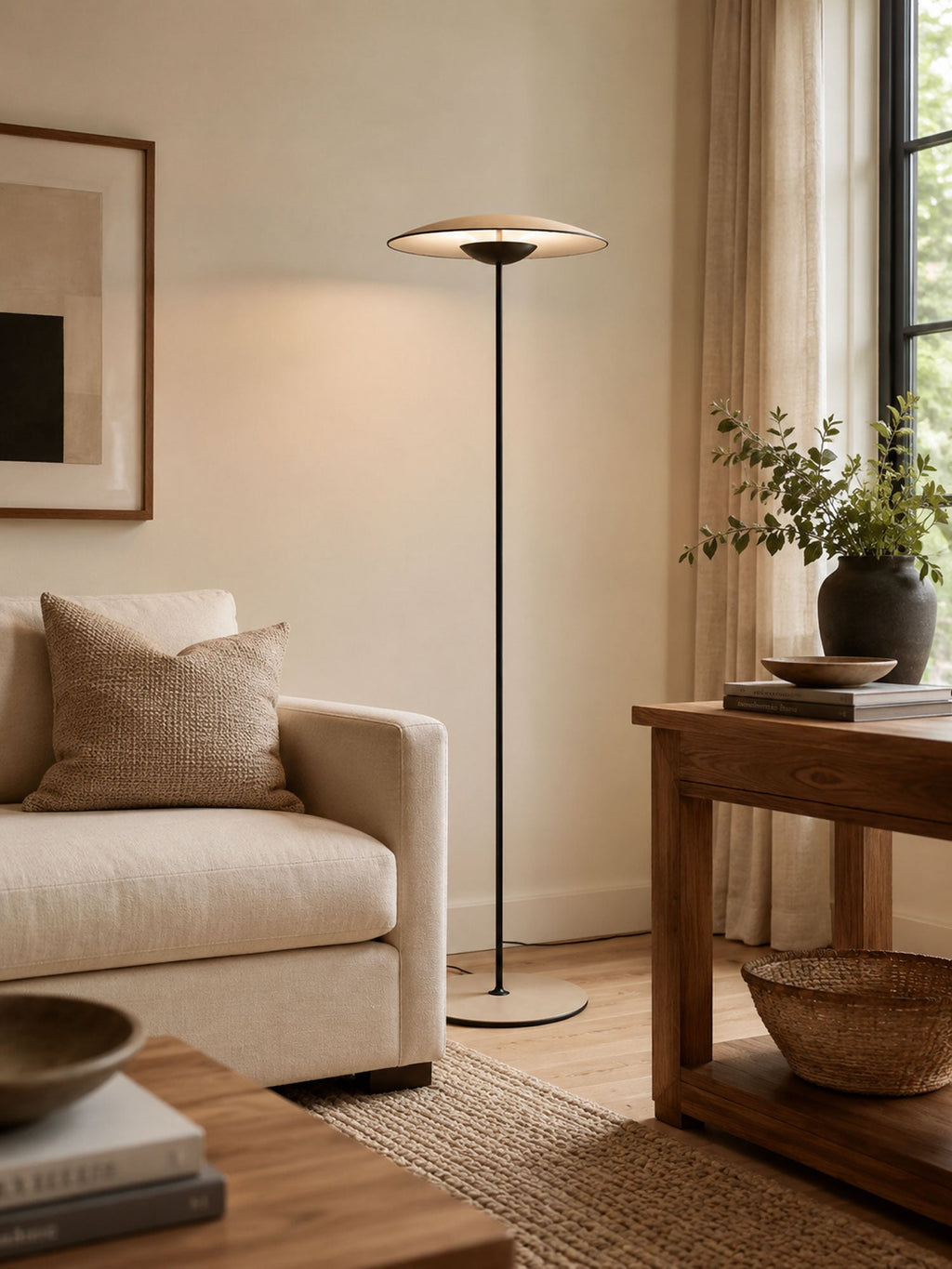 A Clérachic floor lamp rises behind a cream armchair and a small wooden side table, with a woven basket below.