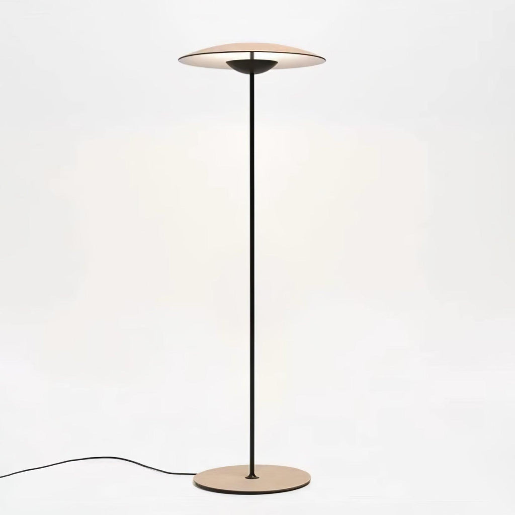 A Clérachic floor lamp with a wood-grain shade, black stem and round base, its cord trailing across a white floor.