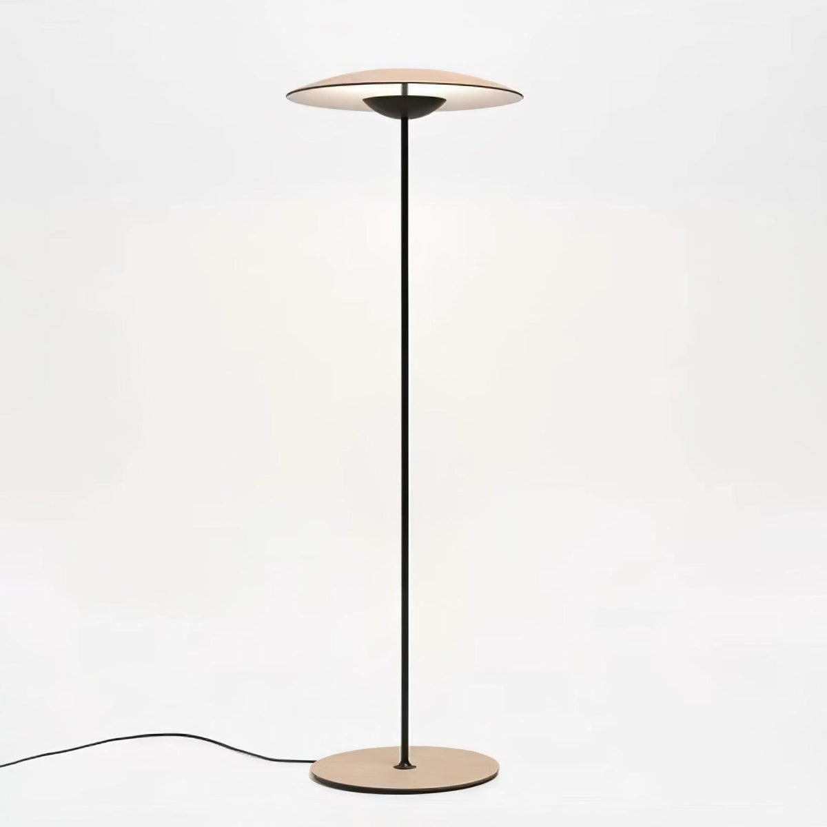 A Clérachic floor lamp with a wood-grain shade, black stem and round base, its cord trailing across a white floor.