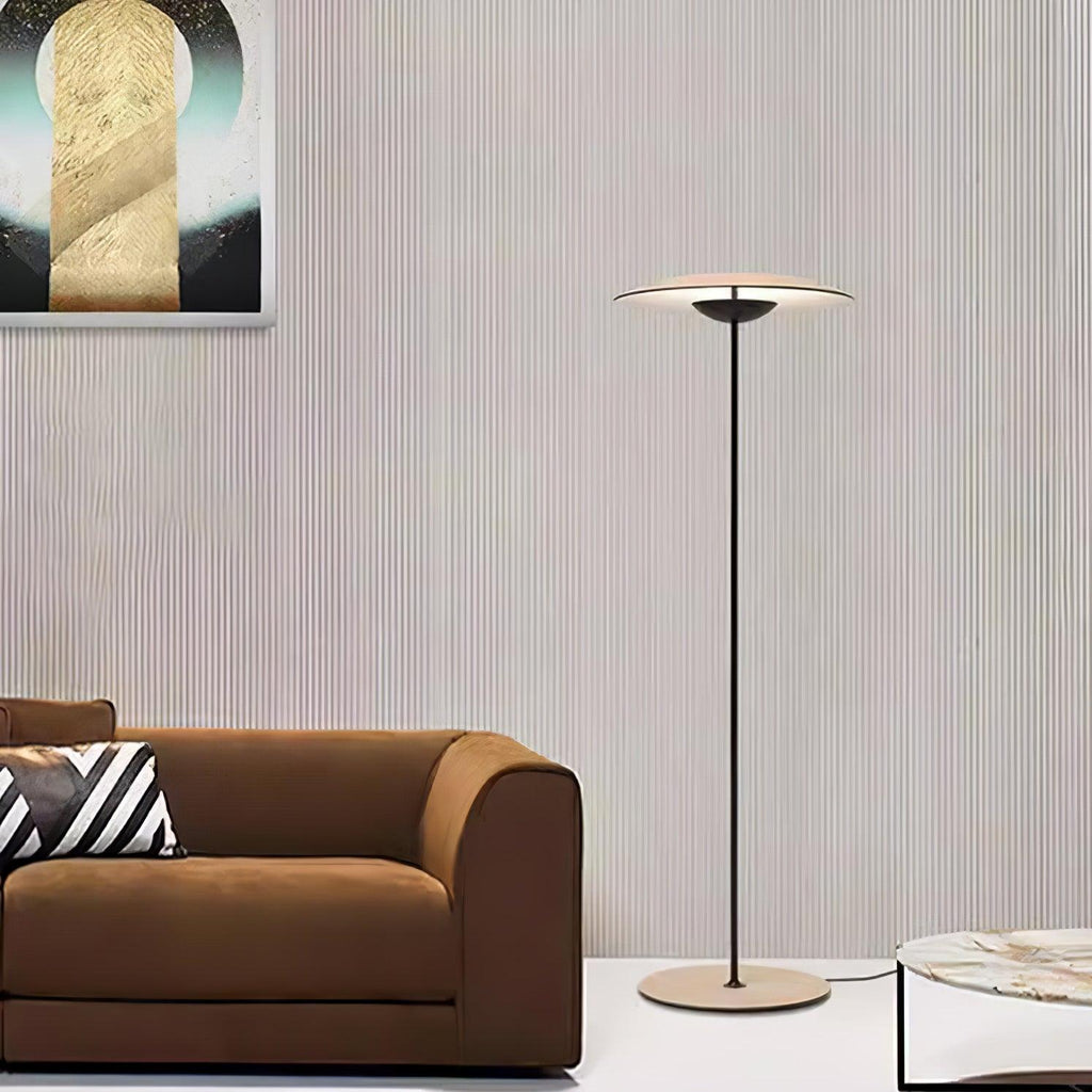 A Clérachic floor lamp stands against a ribbed wall beside a brown sofa and a marble table, with abstract art above.