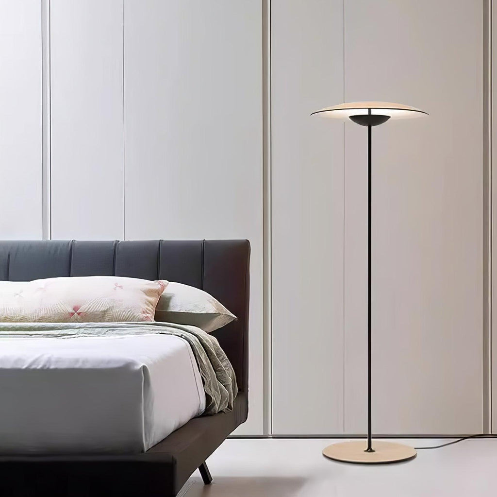 Beside a low bed with a dark headboard, this Clérachic floor lamp stands against pale panelled doors.