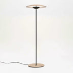 This Clérachic floor lamp on a pale backdrop, with its black cord trailing along the floor from the round base.