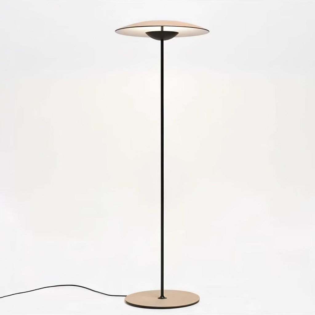 A Clérachic floor lamp on a soft cream backdrop, its glowing disc shade held on a thin black stem above a wood-grain base.