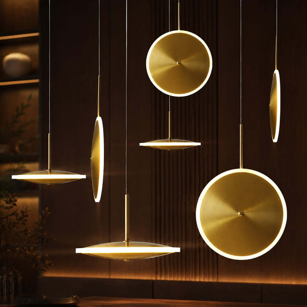 A cluster of Clérachic brushed gold disc pendants, horizontal and vertical, glow at different heights against a dark slatted wall.