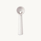 White textured resin Clérachic floor lamp with a tapering stem and a bowl-shaped shade holding a round white bulb, on a plain backdrop.