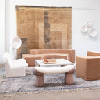 White Clérachic floor lamp at the back of a lounge with a pale armchair, a pink-toned sofa and a rug on the wall.