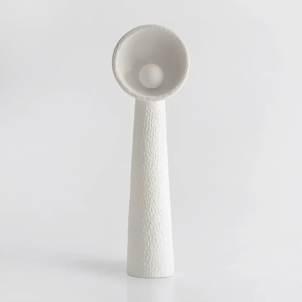 White Clérachic floor lamp with a rough, hand-formed finish and a round bulb in the bowl, on a pale grey backdrop.