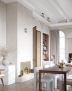 White Clérachic floor lamp in a dining and living space with arched windows, a wooden table and grey stools.