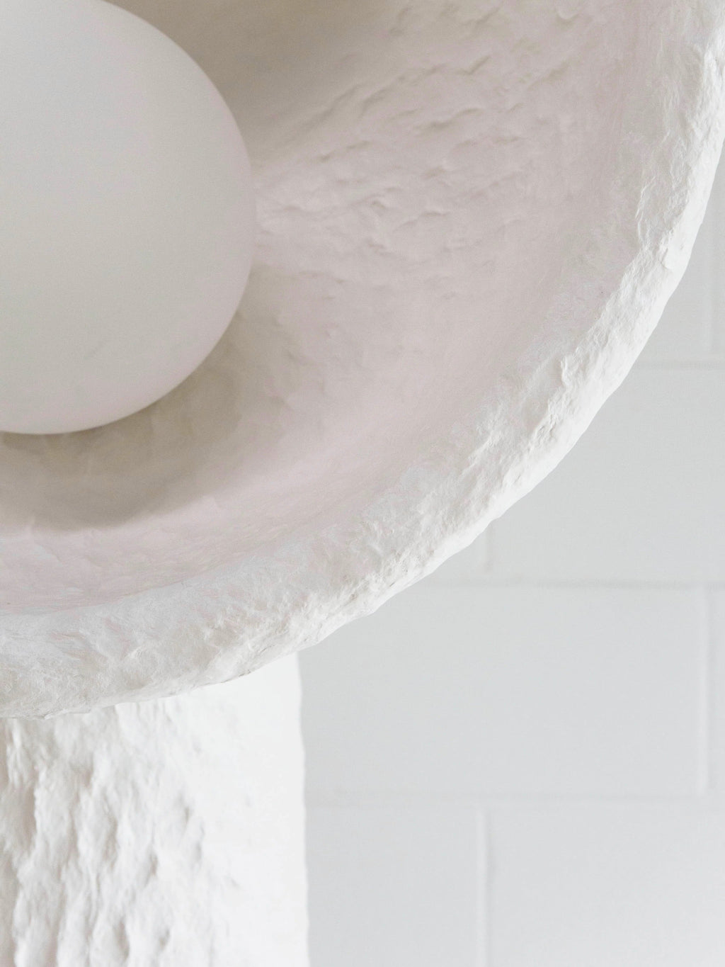 Close view of the lamp's bowl rim, its rough texture and the round white bulb on this Clérachic floor lamp.