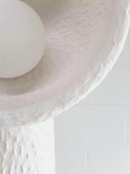 Close view of the lamp's bowl rim, its rough texture and the round white bulb on this Clérachic floor lamp.