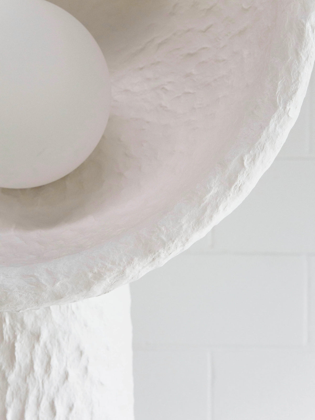 Close view of the lamp's bowl rim, its rough texture and the round white bulb on this Clérachic floor lamp.