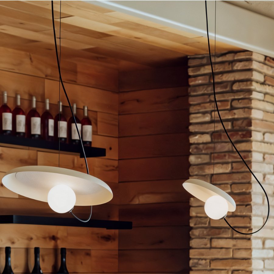 Two Clérachic cream disc pendants with opal globes hung over a wine shelf, timber panelling and a brick column.