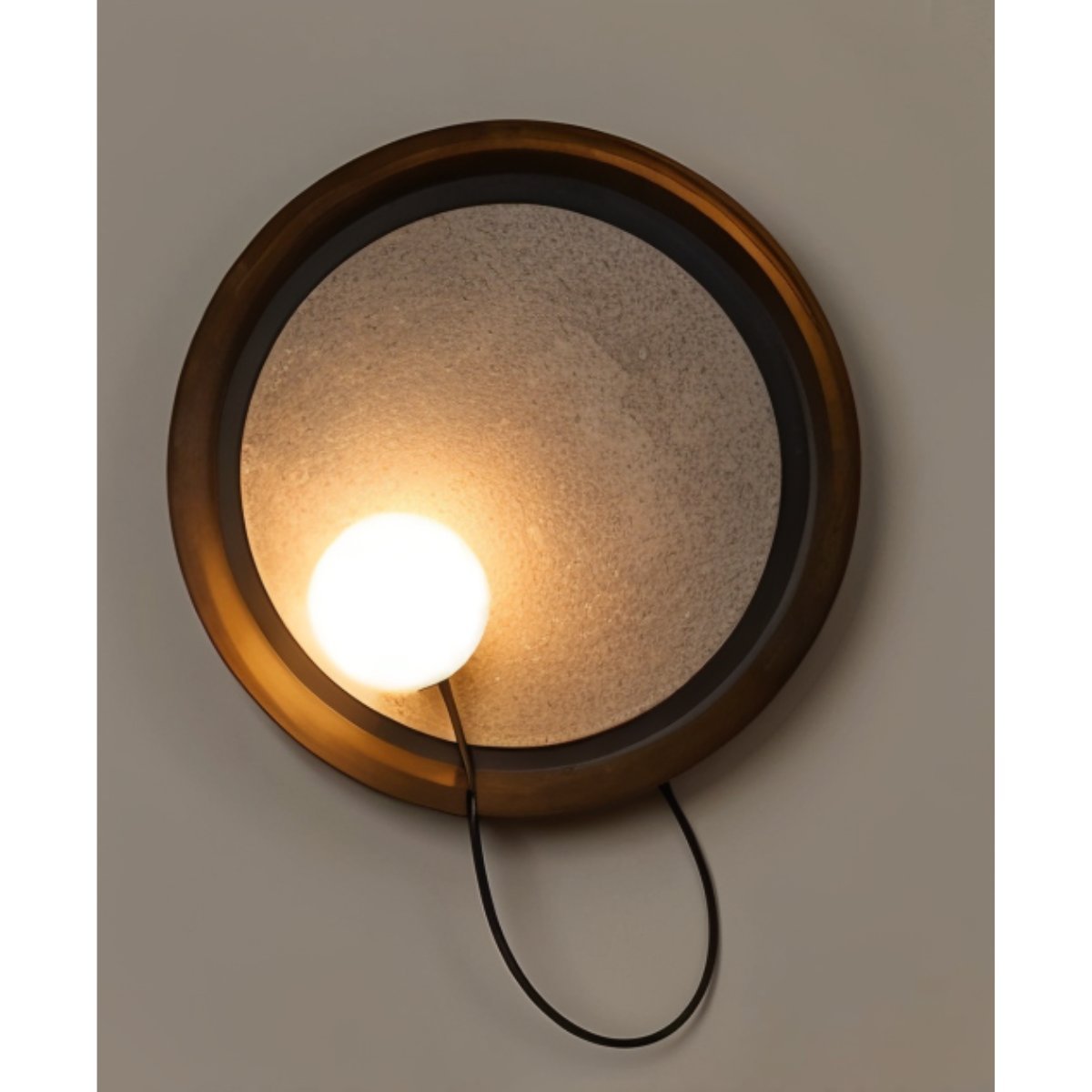 Round Clérachic wall-mounted light with a bronze rim, textured glass centre and a lit opal globe on a looping cord.