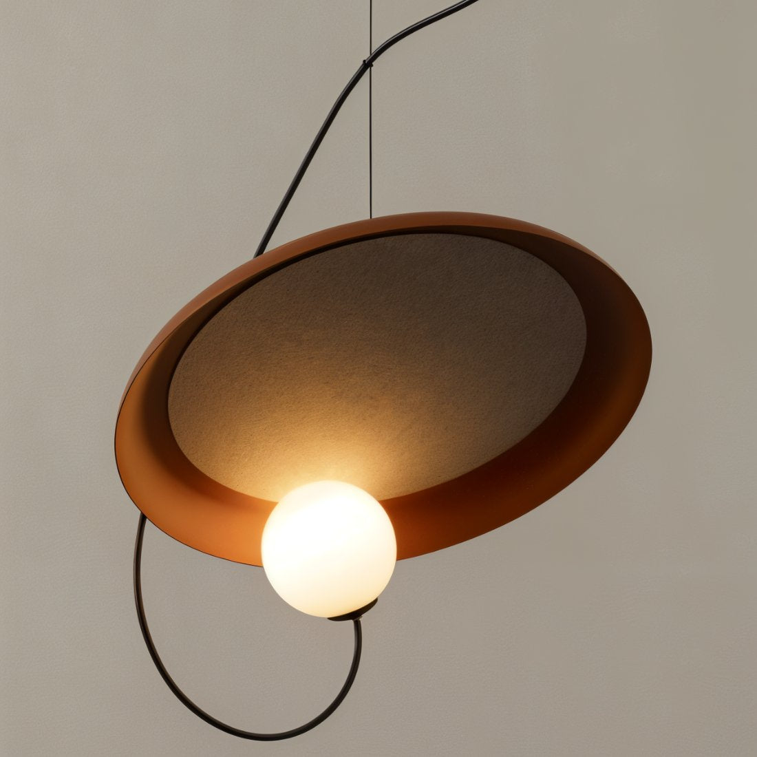 Close view of a Clérachic pendant with a terracotta disc, a textured glass underside and a glowing opal globe.
