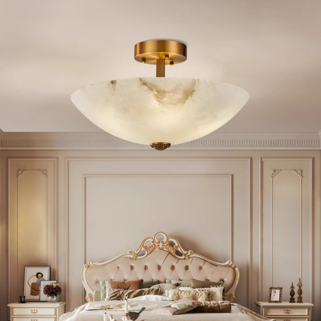 Lit alabaster dome of this Clérachic ceiling light above a tufted cream bed in a panelled, traditional bedroom.