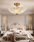 Full bedroom view with this Clérachic alabaster ceiling light centred over an ornate bed, a throw draped on the bench at its foot.
