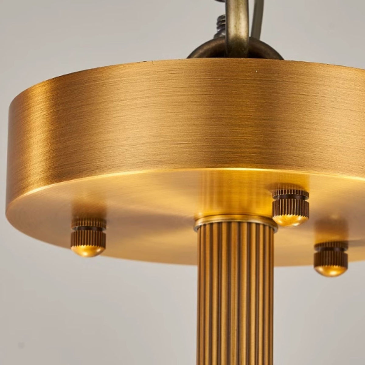 Close view of the brushed brass canopy, three fixing screws and the fluted stem on this Clérachic ceiling light.