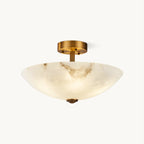 This Clérachic semi-flush light on a white backdrop, lit, its alabaster glowing warm beneath the brass canopy.