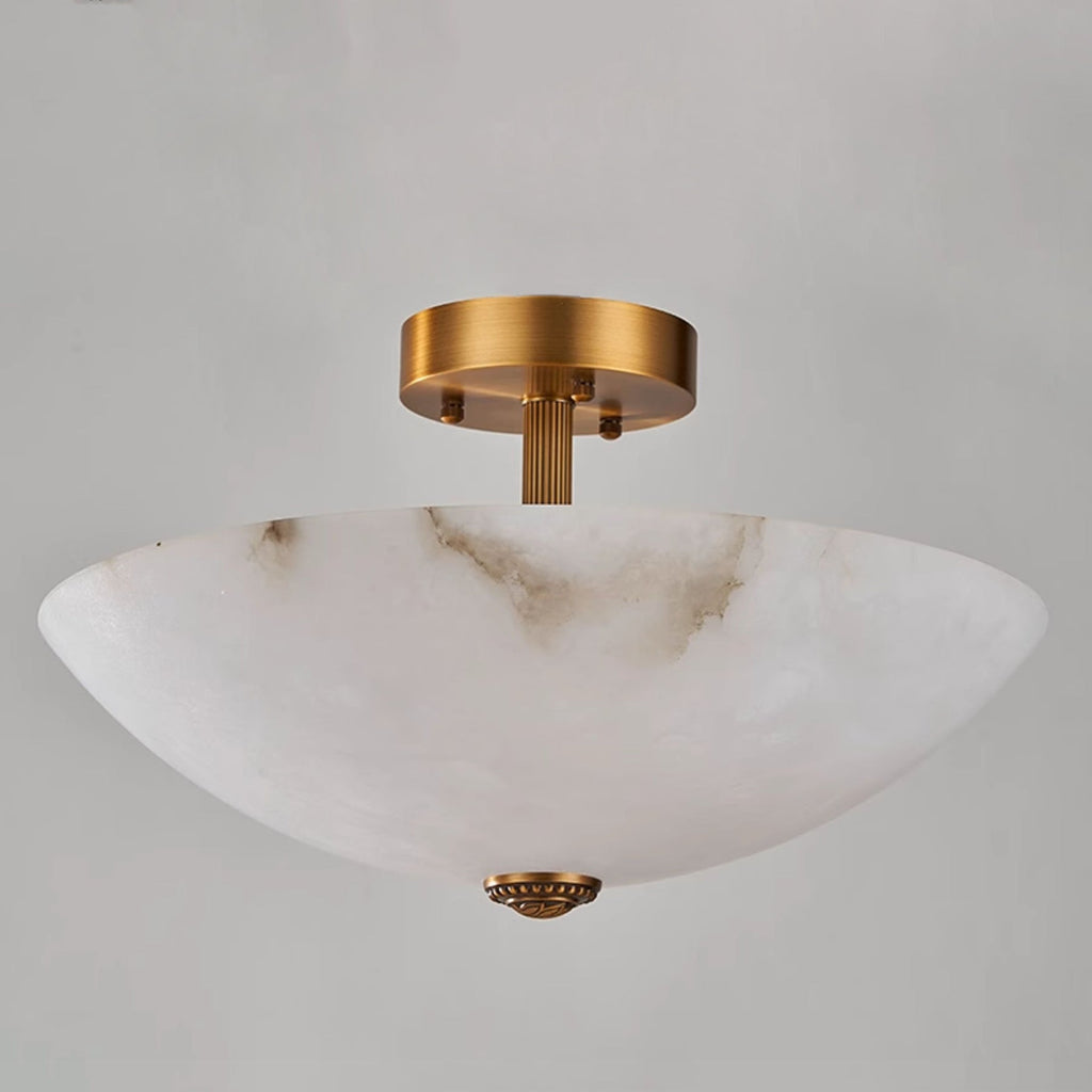 Low, close angle on this Clérachic alabaster dome, showing its deep bowl, fluted brass stem and finial against grey.