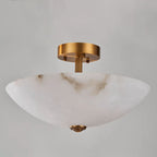 Low, close angle on this Clérachic alabaster dome, showing its deep bowl, fluted brass stem and finial against grey.