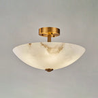 Lit alabaster dome of this Clérachic ceiling light on a grey backdrop, with a warm glow across the stone.