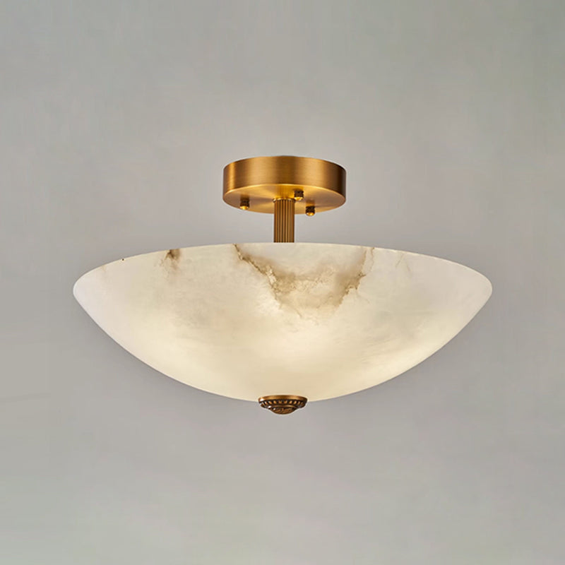 Lit alabaster dome of this Clérachic ceiling light on a grey backdrop, with a warm glow across the stone.