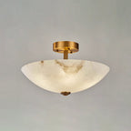 Front view of this Clérachic ceiling light on grey, the alabaster bowl glowing softly under its short brass stem.