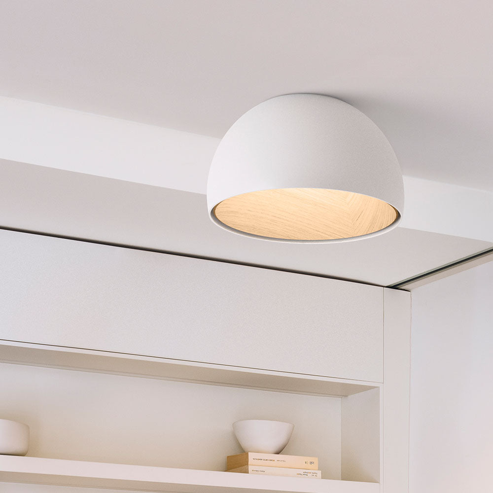 White Clérachic dome ceiling light with an oak interior, mounted flush above a white shelving niche.