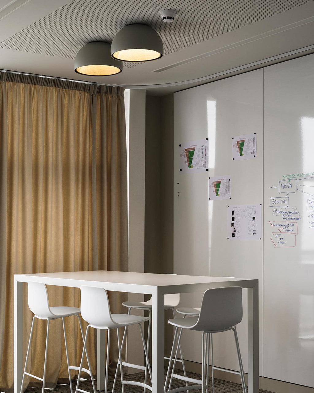 Black and grey Clérachic dome ceiling lights close together above a white high table with white stools and a curtain at the window.