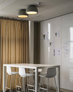 Black and grey Clérachic dome ceiling lights close together above a white high table with white stools and a curtain at the window.